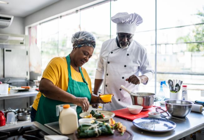 A coach mentors a trainee at a restaurant.