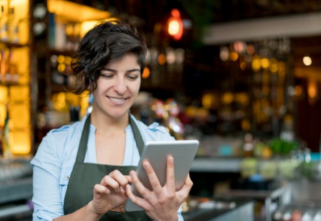 A woman uses technology to complete training in a restaurant.