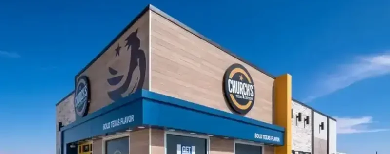 Exterior of a Church's Texas Chicken restaurant with blue awning and clear sky.