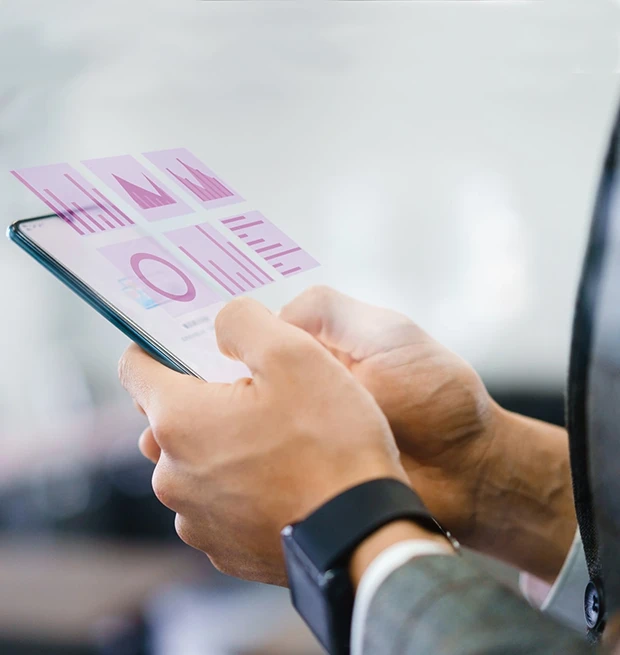 A person holding a smartphone displaying graphs and data visuals with a blurred background.