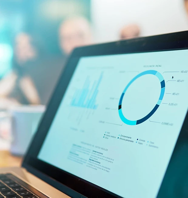 A laptop displaying data visuals with graphs and charts during a meeting.