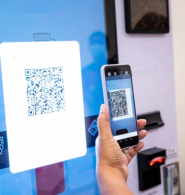 A person scanning a QR code on a display with a smartphone in a vending area.
