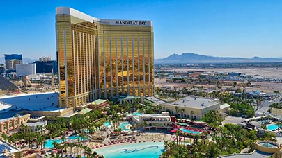 Mandalay Bay Hotel with a large pool area and palm trees under a clear blue sky.