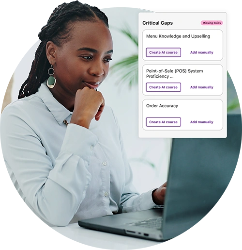 A woman with braided hair working on a laptop, reviewing critical skill gaps on the screen.