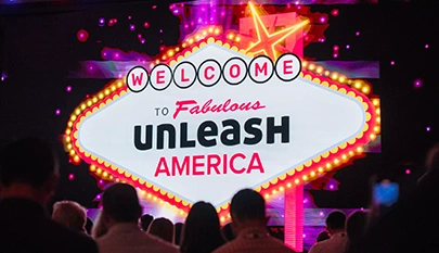 A colorful sign that reads 'Welcome to Fabulous UNLEASH America' with lights, viewed by an audience.