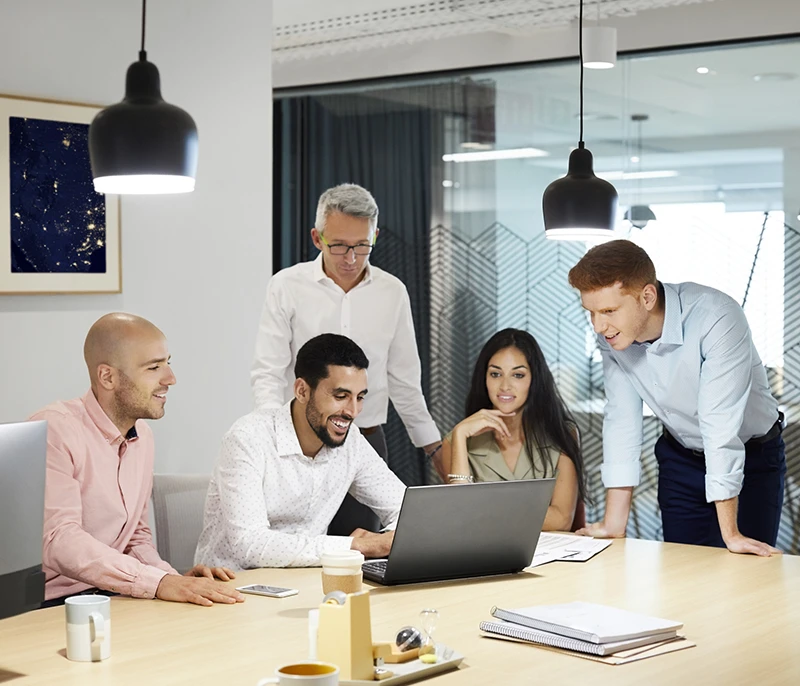 Team of professionals collaborating around a laptop during an office meeting