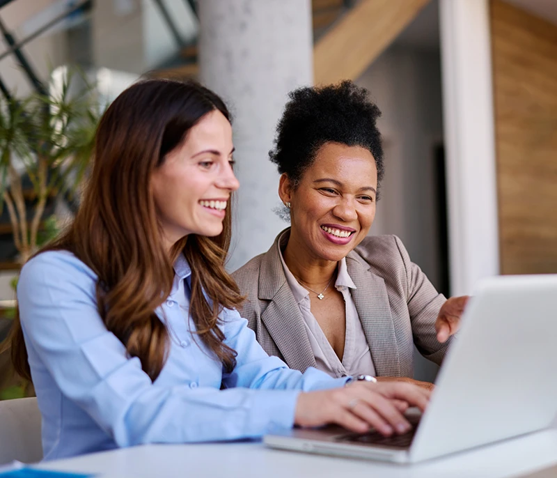 Two business professionals collaborating while using a laptop