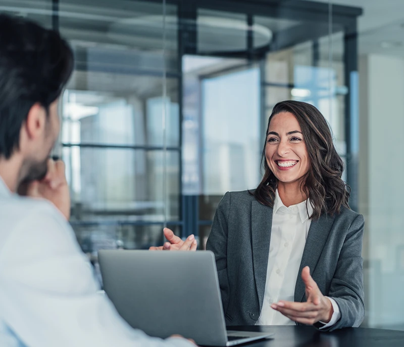 Two professionals discussing ideas during a meeting with a laptop