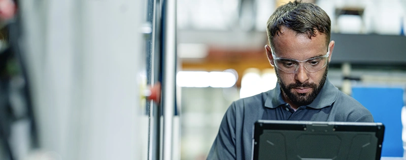 Industrial worker wearing safety glasses using a tablet on the job