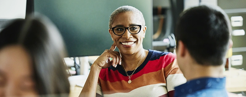Business professional smiling and listening while talking with colleagues in a meeting setting