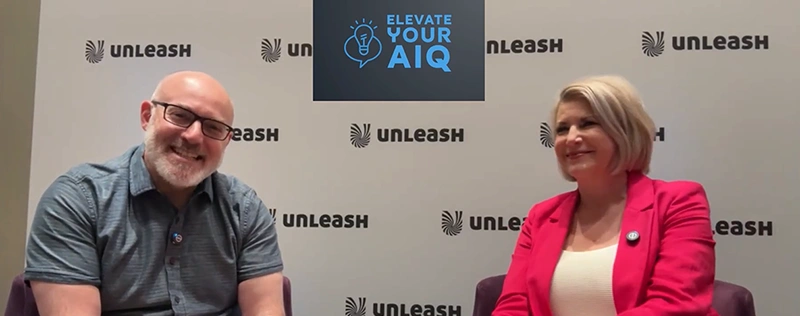 Interview setup with two speakers seated on stage, UNLEASH backdrop, and “Elevate Your AIQ” title displayed above