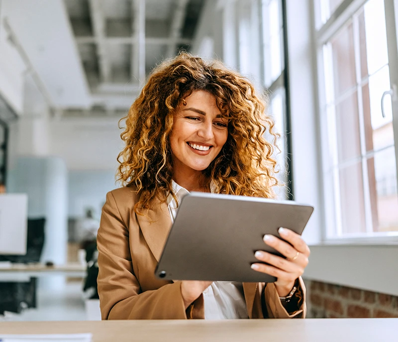 Business professional smiling while using a tablet in a modern office