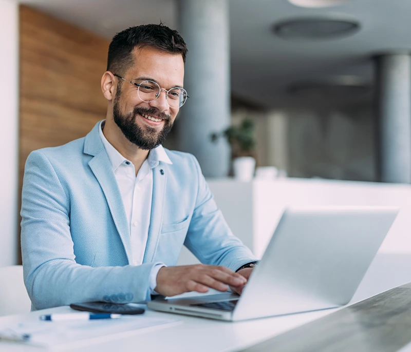 Business professional smiling while working on a laptop in a modern office