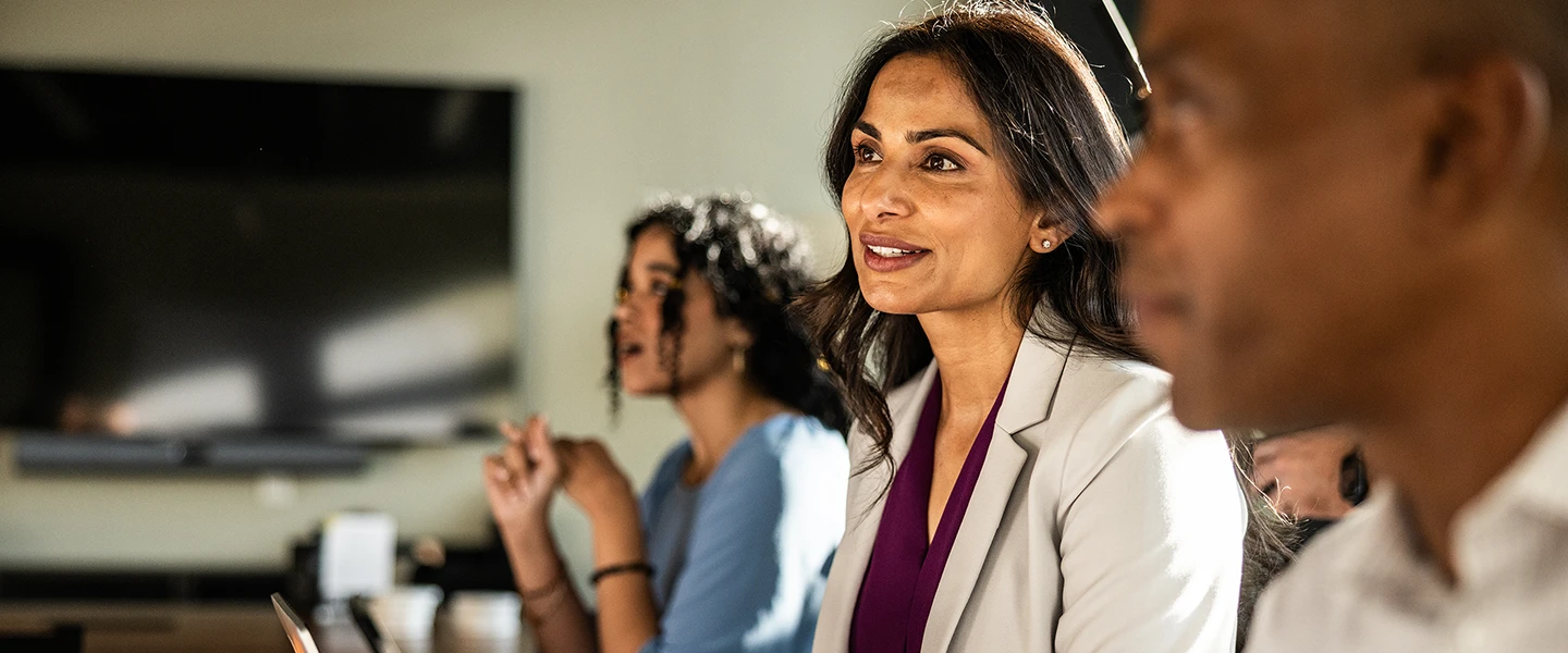 Business team engaged in a meeting, discussing ideas while using laptops at a conference table