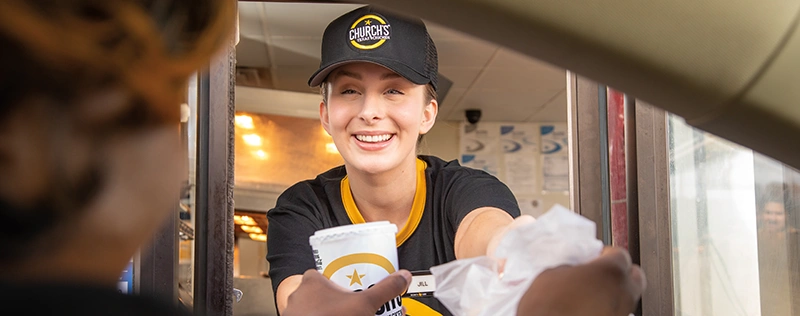 Church's Texas Chicken employee serving a customer through a drive-thru window