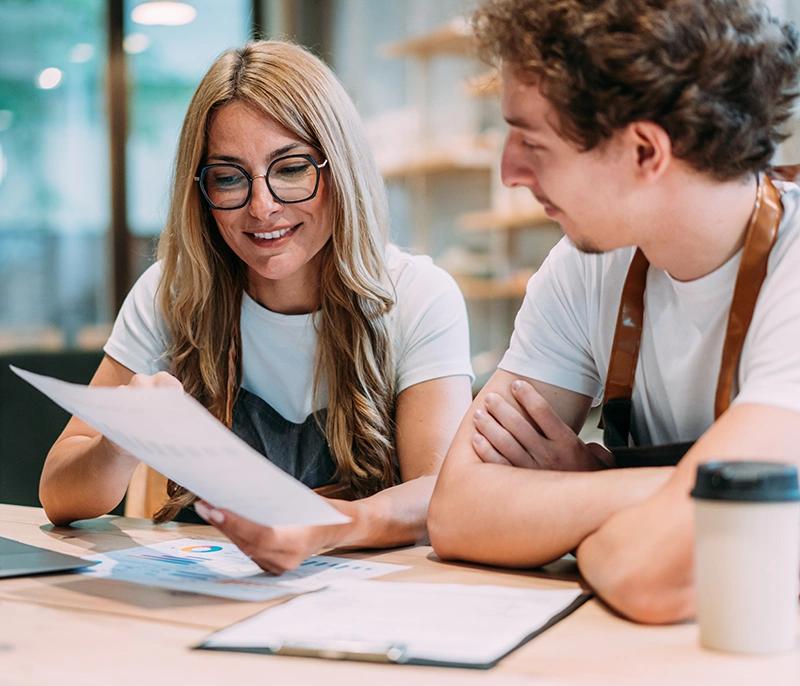 Two frontline employees reviewing training materials together at a table