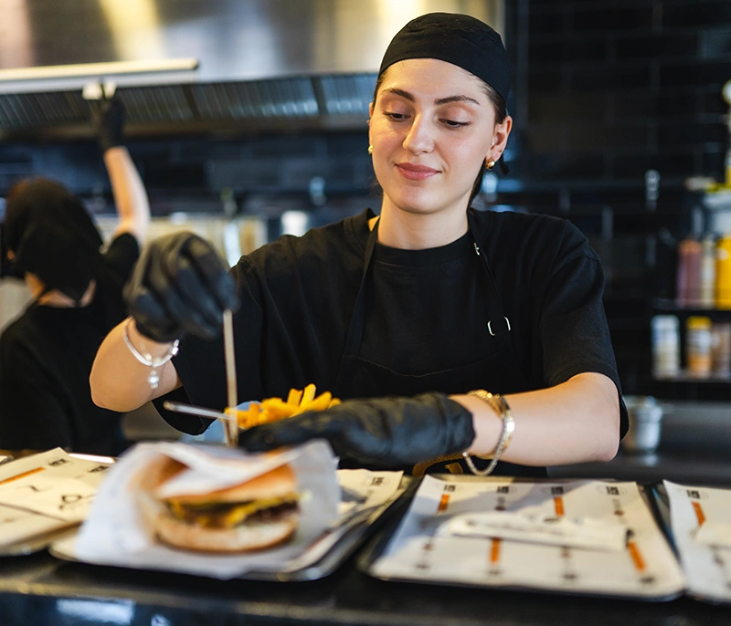 Quick-service restaurant employee preparing a burger and fries