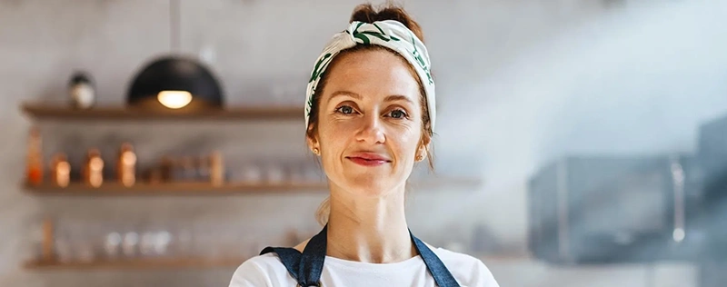 Frontline restaurant employee wearing an apron and smiling in a commercial kitchen
