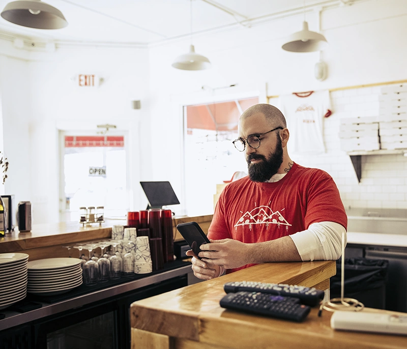 Restaurant employee using a smartphone behind the counter