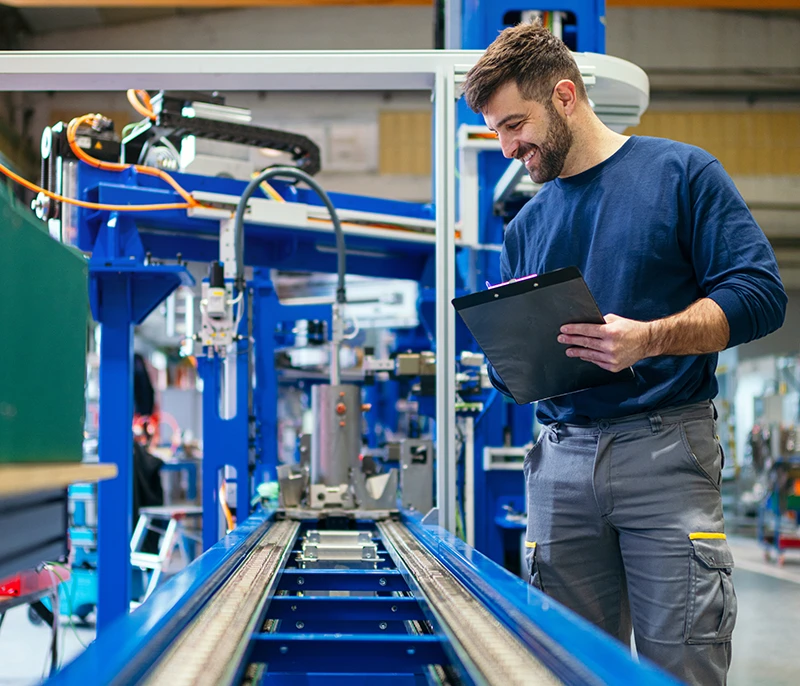 Manufacturing employee reviewing information on a clipboard beside industrial machinery